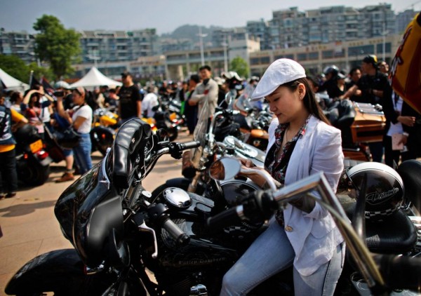 A woman sits on a Harley Davidson motorcycle during the annual rally at Lake Qiandaohu in Zhejiang Province, China.