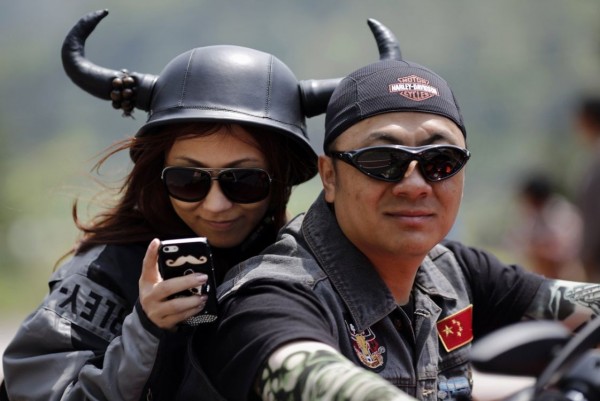 Young man and woman riding a motorcycle Harley Davidson during the annual rally in Qiandaohu Lake in Zhejiang Province, China