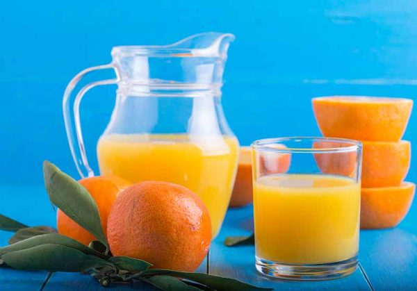 fresh tangerines, oranges, orange juice on a blue background
