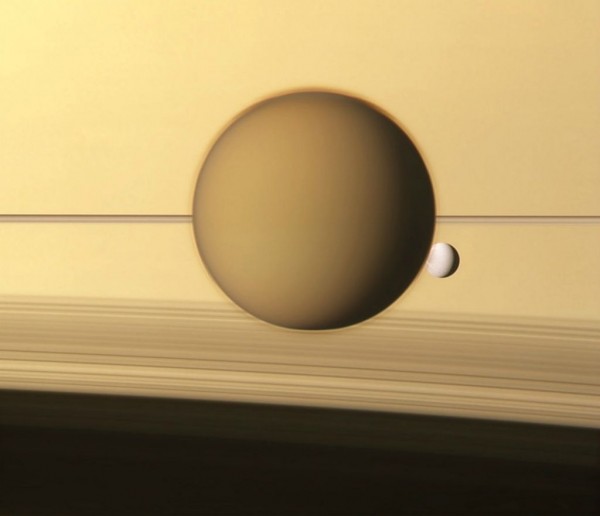Titan and Dione against the outwardly serene atmosphere of Saturn
